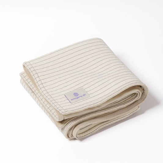 Folded cream Emagene Life striped blanket on white background, functional medicine product