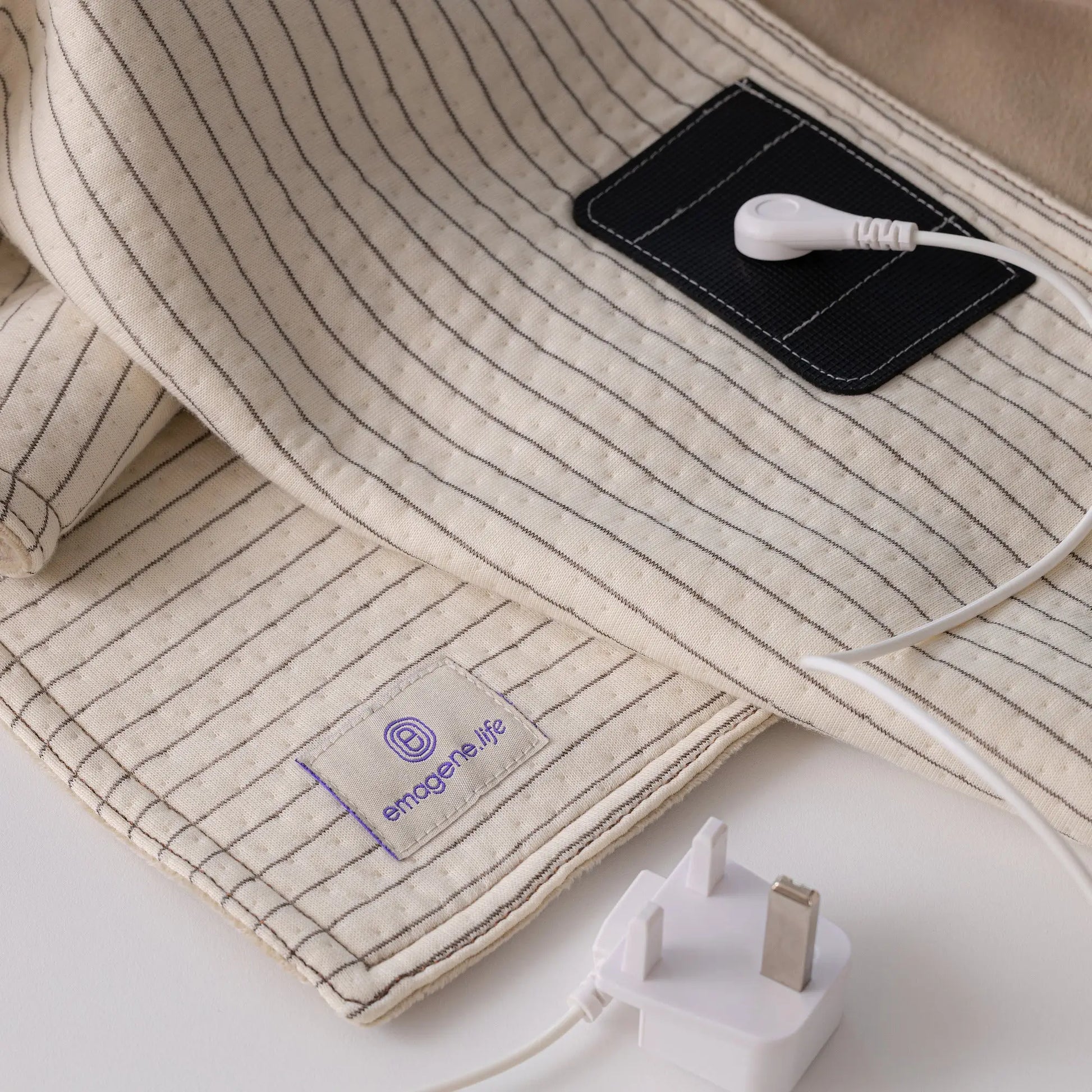 Emagene Life striped fabric pad with USB connector, UK plug, and brand label on white surface