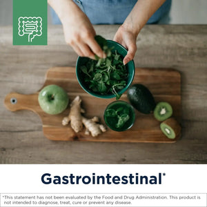 Preparing leafy greens with ginger, kiwi, apple, and avocado on wooden board, gastrointestinal health focus