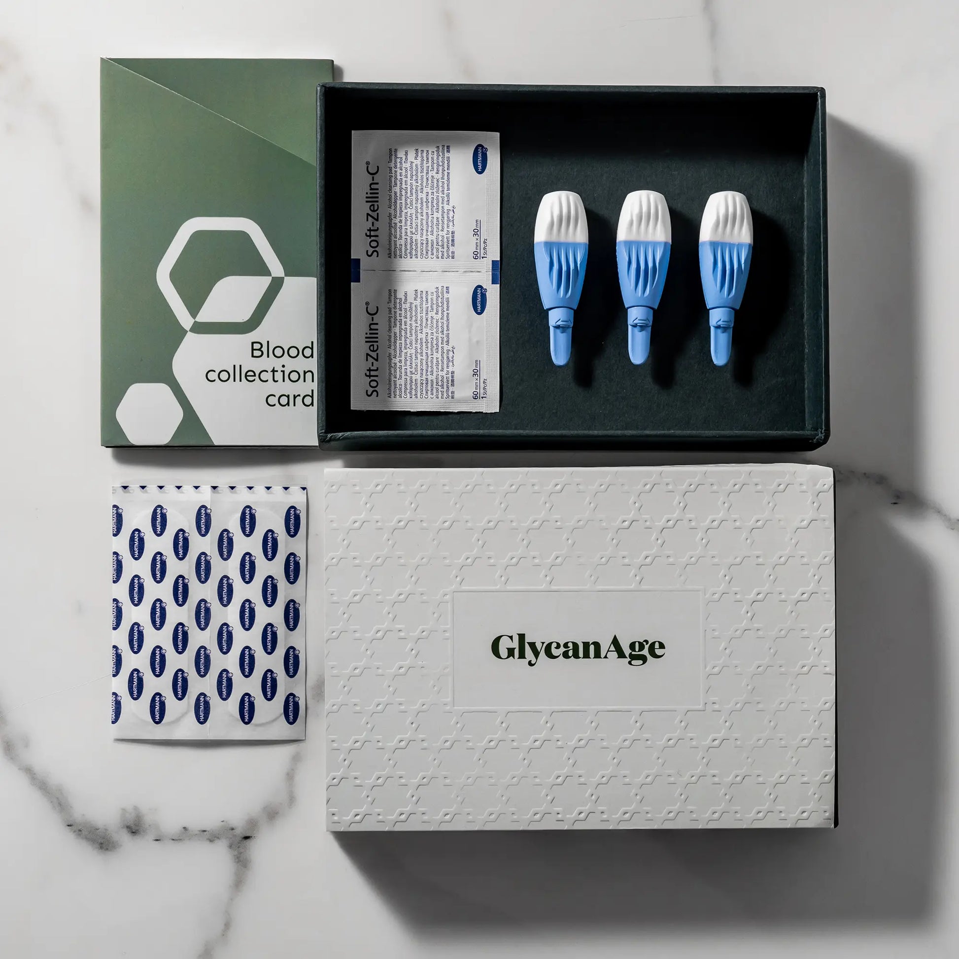 GlycanAge blood test kit with collection card, lancets, antiseptic wipes on marble surface