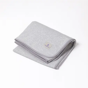 Folded light grey Emagene Life blanket with logo tag on white background