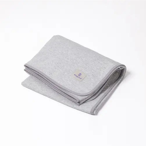 Folded light grey Emagene Life blanket with logo tag on white background
